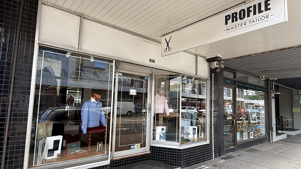 Image of shopfront for Profile by Pino Curcio, with male mannequins in the window dressed smartly with tailored garments, with vintage photographs and sew machines complementing the display