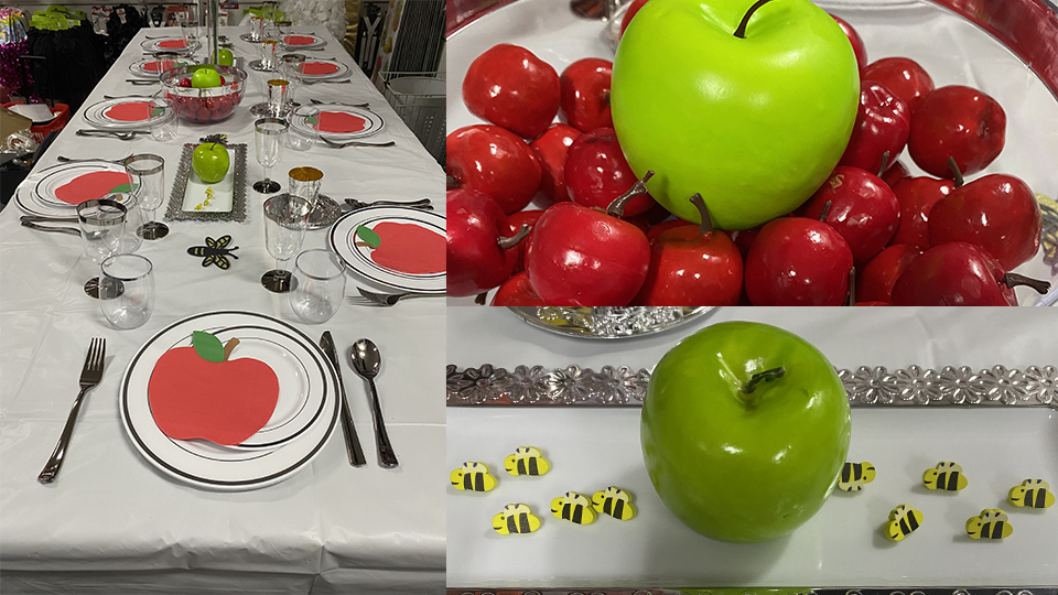 Festive Rosh Hashanah table set with apple-themed place settings, decorative apples and small bee decorations.