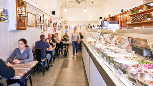 Photo of interior of Talk of the town, with people sitting dining to the left, row of dishes to the right