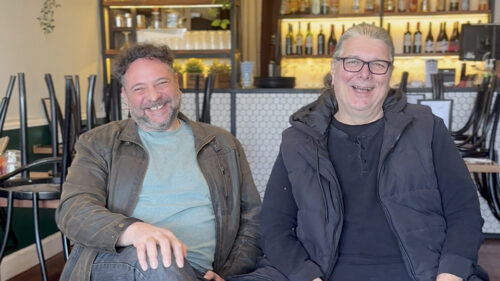 Two Budapest restaurant owners smiling and laughing while seated together inside the Elsternwick restaurant. Left is David Buchler while right is Viktor Sallay.