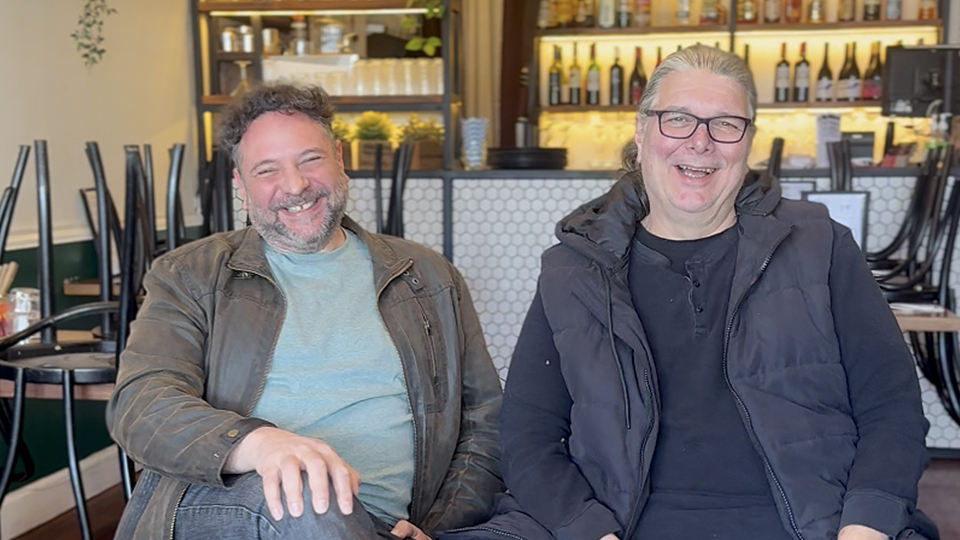 Two Budapest restaurant owners smiling and laughing while seated together inside the Elsternwick restaurant. Left is David Buchler while right is Viktor Sallay.
